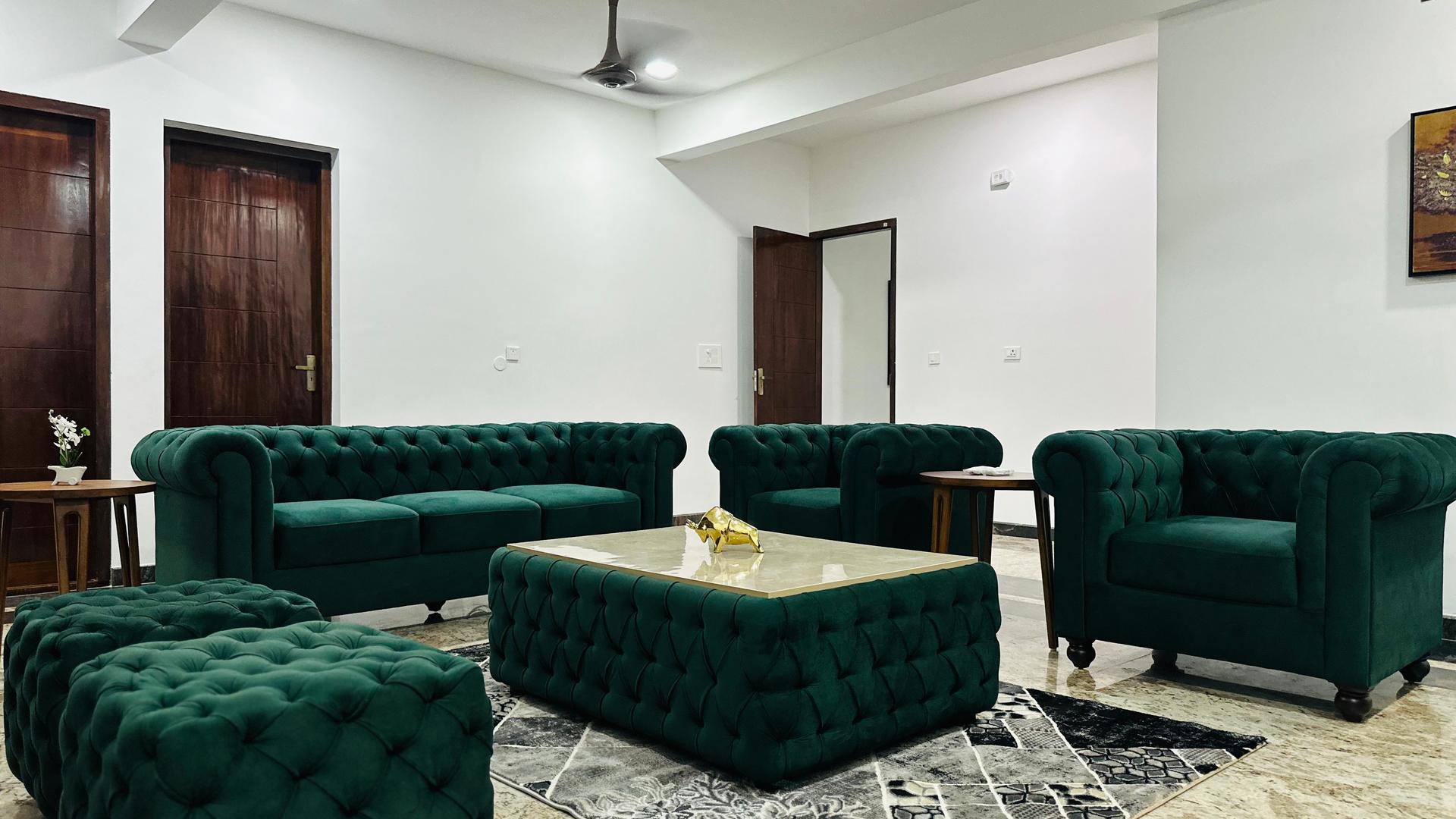Living room of a Cocoon-managed home in Kochi, with velvet seating and teak doors